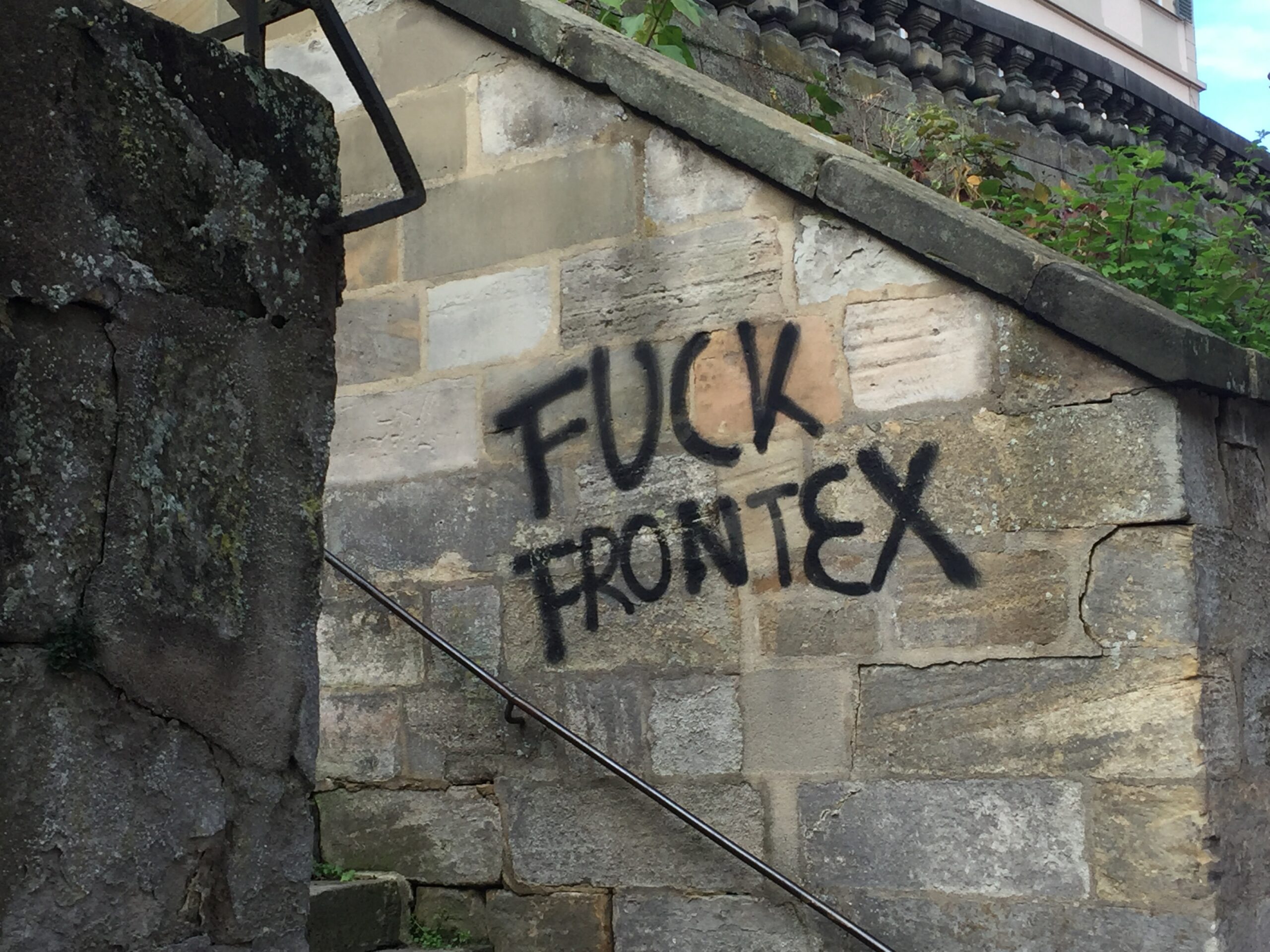 Graffiti on a wall reads 'FUCK FRONTEX'